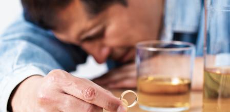 Closeup of a single sad wife after divorce lamenting holding the wedding ring in a house interior