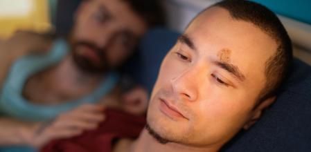 Insulted gay man lying in bed by his boyfriend and ignoring his apology