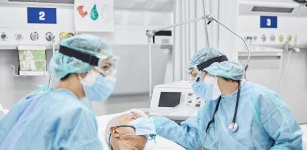 Dos doctores y enfermeros cuidan a un paciente encamado en la UCI