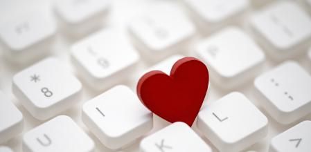 Small red heart on computer keyboard. Internet dating concept.