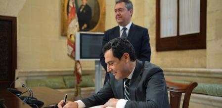 Moreno Bonilla escribe en el libro de honor del Ayuntamiento de Sevilla con Juan Espadas al fondo (Junta de Andalucía)