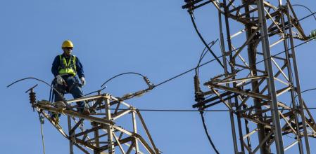 Un operario trabaja en una torre de alta tensión