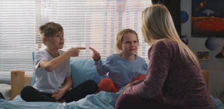Full shot of a mother trying to reconcile bickering siblings