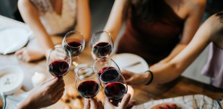 Close up of happy young friends having fun and toasting and celebrating with red wine during party