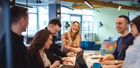 Happy colleagues laughing in the office at the meeting table