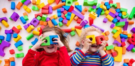 Happy preschool age children play with colorful plastic toy blocks. Creative kindergarten kids build a block tower. Educational toys for toddler or baby. Top view from above. (Happy preschool age children play with colorful plastic toy blocks. Creativ