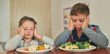 Cropped shot of two grumpy children refusing to eat their vegetables