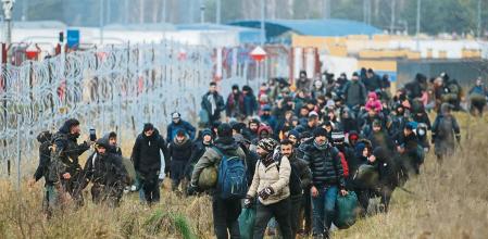 TOPSHOT - A group of migrants moves along the Belarusian-Polish border towards a camp to join those gathered at the spot and aiming to enter EU member Poland, in the Grodno region on November 12, 2021. - Hundreds of desperate migrants are trapped in freezing temperatures on the border and the presence of troops from both sides has raised fears of a confrontation. (Photo by Leonid Shcheglov / BELTA / AFP) / Belarus OUT