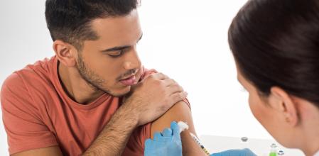 Selective focus of doctor doing injection to handsome patient isolated on white