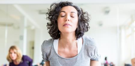 Mature women stretching in the fitness center. Mid adult female practicing the cobra pose during their yoga class in a gym.