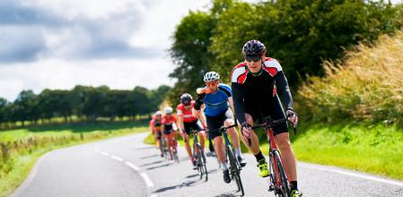 Cyclists racing on country roads on a sunny day in the UK.