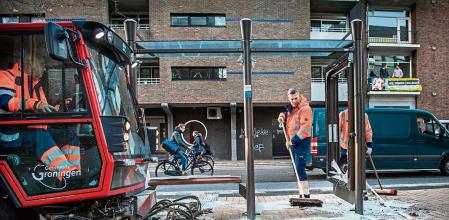 22 November 2021, Netherlands, Groningen: Employees of the cleaning team sweep up broken pieces of a destroyed bus shelter after riots that occurred in the city of Groningen. Rioters started fires, destroyed bus stops and set off heavy fireworks in several Dutch cities late Sunday, the Dutch news agency ANP reported. Photo: Corné Sparidaens/ANP/dpa 22/11/2021 ONLY FOR USE IN SPAIN