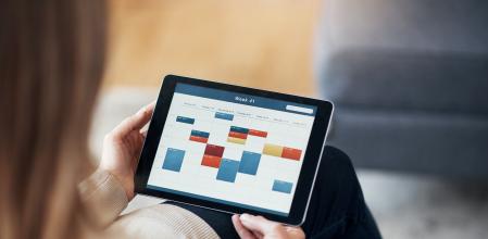 Cropped shot of an unrecognizable woman sitting and viewing a timetable on a tablet in her living room