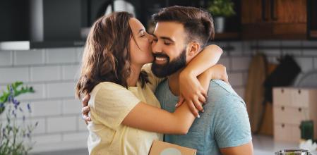Young couple in the kitchen. The man surprised his girlfriend with an unexpected gift. She is happy. Hugging him and kissing.