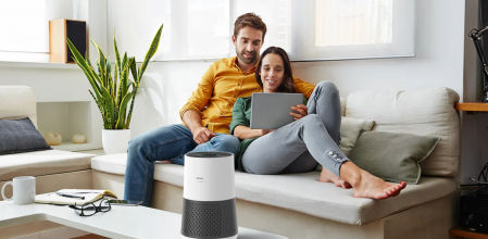Una pareja en el sillón con un purificador de aire Winix