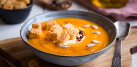 pumpkin soup with croutons on white wooden background