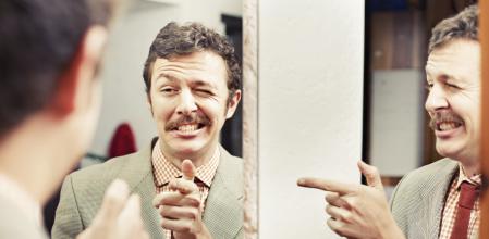Man pointing at reflection in mirror
