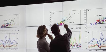 Business men in a dark room standing in front of a large data display