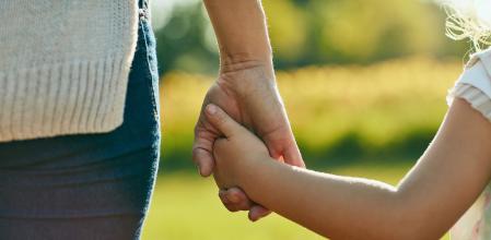 Cropped shot of a little girl holding an unrecognizable woman’s hand in the park