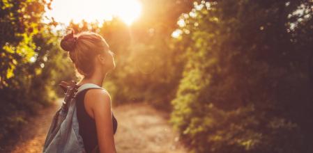 Photo of a young woman with a backpack, wandering around in nature and relaxing