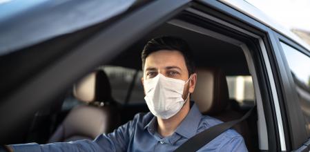 Un conductor de un vehículo lleva puesta una mascarilla