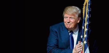 U.S. Republican presidential candidate Donald Trump hugs a U.S. flag as he takes the stage for a campaign town hall meeting in Derry, New Hampshire, United States August 19, 2015. REUTERS/Brian Snyder SEARCH - PICTURES OF THE YEAR 2015 - FOR ALL IMAGES TPX IMAGES OF THE DAY