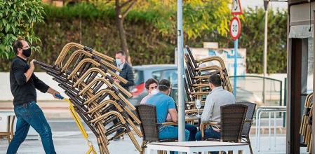 GRAFAND3939. SEVILLA, 10/11/2020.-Camareros de un bar de Mairena del Aljarafe(Sevilla) recogen el mobiliario para proceder al cierre antes de las seis de la tarde hoy martes cuando Andalucía ha iniciado a las 0:00 horas dos semanas de medidas restrictivas para intentar contener los brotes de coronavirus, que contemplan, entre otras cosas, adelantar el toque de queda desde las 10 de la noche a las 7 de la mañana y limitar la actividad comercial no esencial hasta las seis de la tarde, excepto en Granada, donde hay cierre total. EFE/José Manuel Vidal