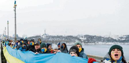 People form a human chain along a bridge across the Dnipro River as they celebrate the Day of Unity in Kyiv, Ukraine January 22, 2022. REUTERS/Valentyn Ogirenko