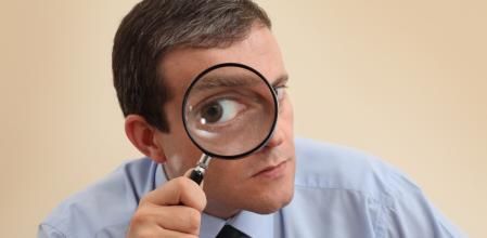 Businessman looking through magnifying glass. Focus on his hand and magnifying glass.