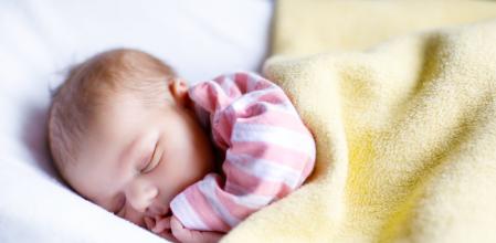 Cute adorable newborn baby sleeping in white bed. New born child, little girl laying in bed. Family, new life, childhood, beginning concept.