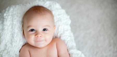 Little baby boy playing at home with soft teddy bear toys, lying down
