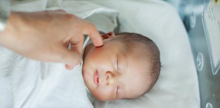 Newborn baby boy asleep in hospital bassinet