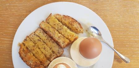 Huevos pasados por agua con sal y pimienta, y una rebanada de pan con aceite de oliva extra virgen y miel