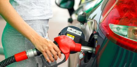 Woman fills petrol into her car at a gas station