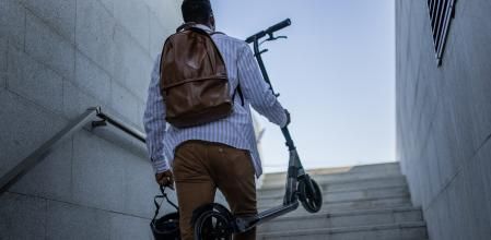 Hombre con patinete sube unas escaleras