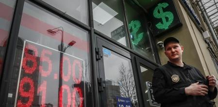 Un vigilante custodia la entrada de un centro de cambio de divisas en Moscú, este mes, con el símbolo del dólar de fondo