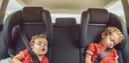 Dos hermanos descansan en sus sillas de retención con el cinturón de seguridad abrochado