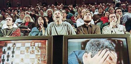 Chess enthusiasts watch World Chess champion Garry Kasparov on a television monitor as he holds his head in his hands at the start of the sixth and final match 11 May 1997 against IBM's Deep Blue computer in New York. Kasparov lost this match in just 19 moves giving overall victory to Deep Blue with a score of 2.5-3.5. / AFP / STAN HONDA (Photo credit should read STAN HONDA/AFP via Getty Images)