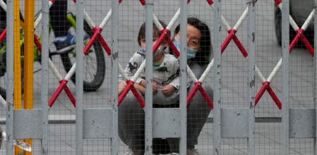 A resident and a child look out through gaps in the barriers at a closed residential area during lockdown, amid the coronavirus disease (COVID-19) pandemic, in Shanghai, China, May 10, 2022. REUTERS/Aly Song      TPX IMAGES OF THE DAY