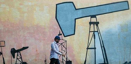 AME2985. CARACAS (VENEZUELA), 22/04/2022.- Un hombre pasa frente a un mural que muestra el proceso de extracción de petróleo frente a una sede de la estatal Petróleos de Venezuela S.A (Pdvsa), el 21 de abril de 2022, en Caracas (Venezuela). La recuperación de la producción petrolera de Venezuela, que de 3,2 millones de barriles por día (bpd) en 1998 pasó a no superar ahora el millón, es una de las principales metas del presidente Nicolás Maduro en medio de la crisis energética mundial, pero, a juicio de expertos, difícil de alcanzar sin una resolución del conflicto político interno y con las sanciones aún vigentes. EFE/ Ronald Peña