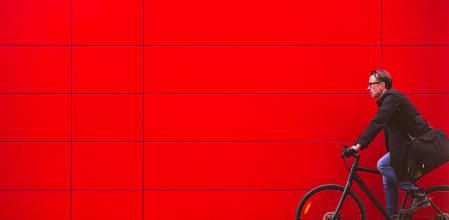 Un hombre en bici ante una pared roja