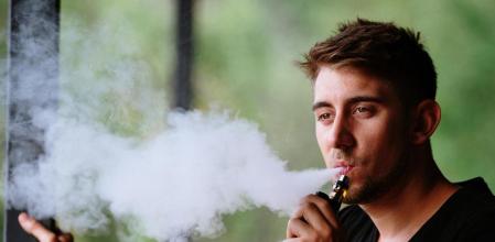 Un joven vapeando con un cigarrillo electrónico