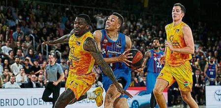 BARCELONA, 27/05/2022.- El alero australiano del Barça, Dante Exum (d), con el balón ante el escolta canadiense del Gran Canaria, Dylan Ennis, durante el primer partido de los cuartos de final del playoff de la Liga Endesa 2021/2022 disputado este viernes en el Palau Blaugrana. EFE/Alejandro García