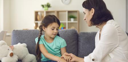 Una madre habla con su hija mientras sostiene cariñosamente sus manos