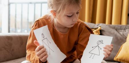 Niña sosteniendo dibujos de su padre y madre