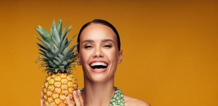 Una mujer sonriente sostiene una piña