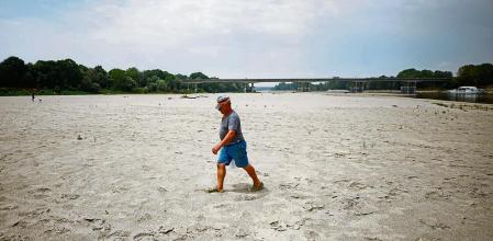 A man walks on Po's dry riverbed as parts of Italy's longest river and largest reservoir of freshwater have dried up due to the worst drought in the last 70 years, in Boretto, Italy, June 22, 2022. REUTERS/Guglielmo Mangiapane