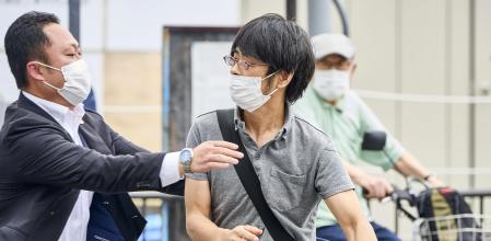 Tetsuya Yamagami, left, holding a weapon, is detained near the site of gunshots in Nara, western Japan Friday, July 8, 2022. Former Prime Minister Shinzo Abe was assassinated Friday on a street in western Japan by Yamagami, a gunman who opened fire on him from behind as he delivered a campaign speech — an attack that stunned the nation that has some of the strictest gun control laws anywhere.(Nara Shimbun/Kyodo News via AP)