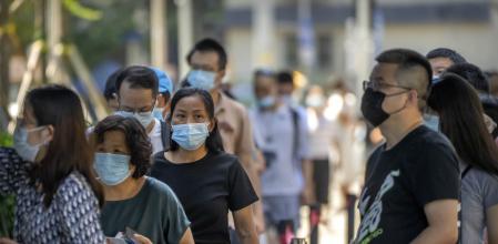 Personas con mascarilla esperan en fila para las pruebas de COVID-19 en Beijing