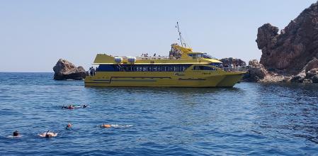 Bañistas en las Medas cerca de un barco turístico.